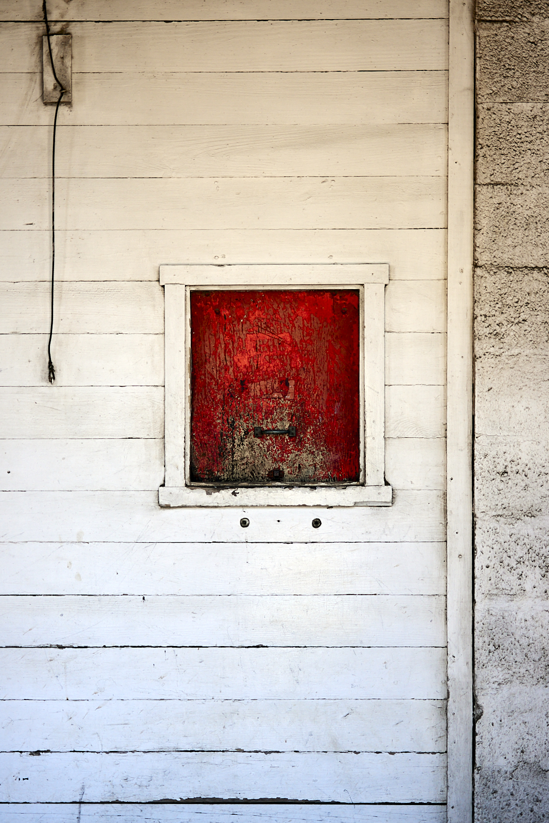 #220424.1 A color photograph of a small, red feed door at the local horse farm.