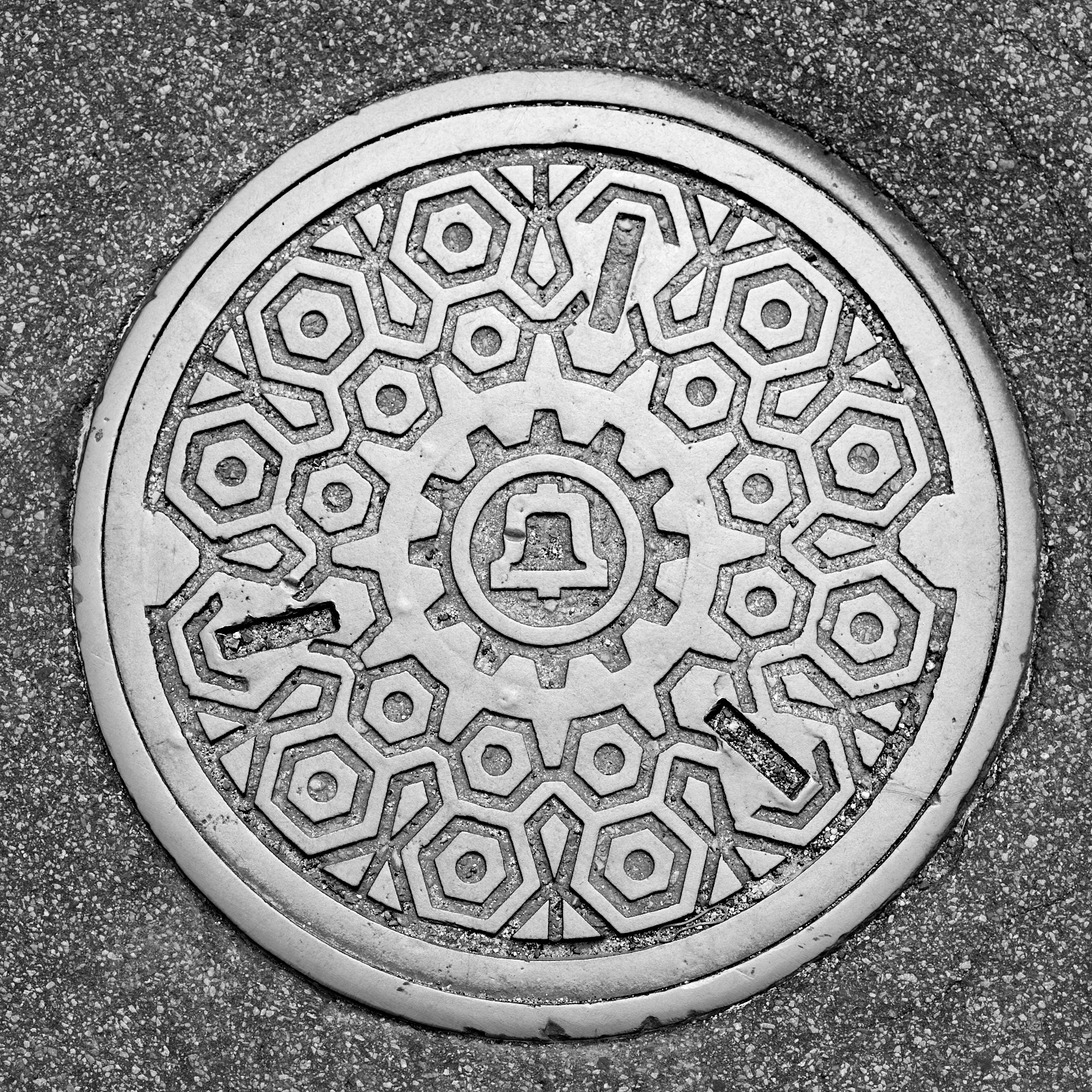 Infrastructure #220621.1. A black and white photograph of a Bell Systems manhole cover in a street.