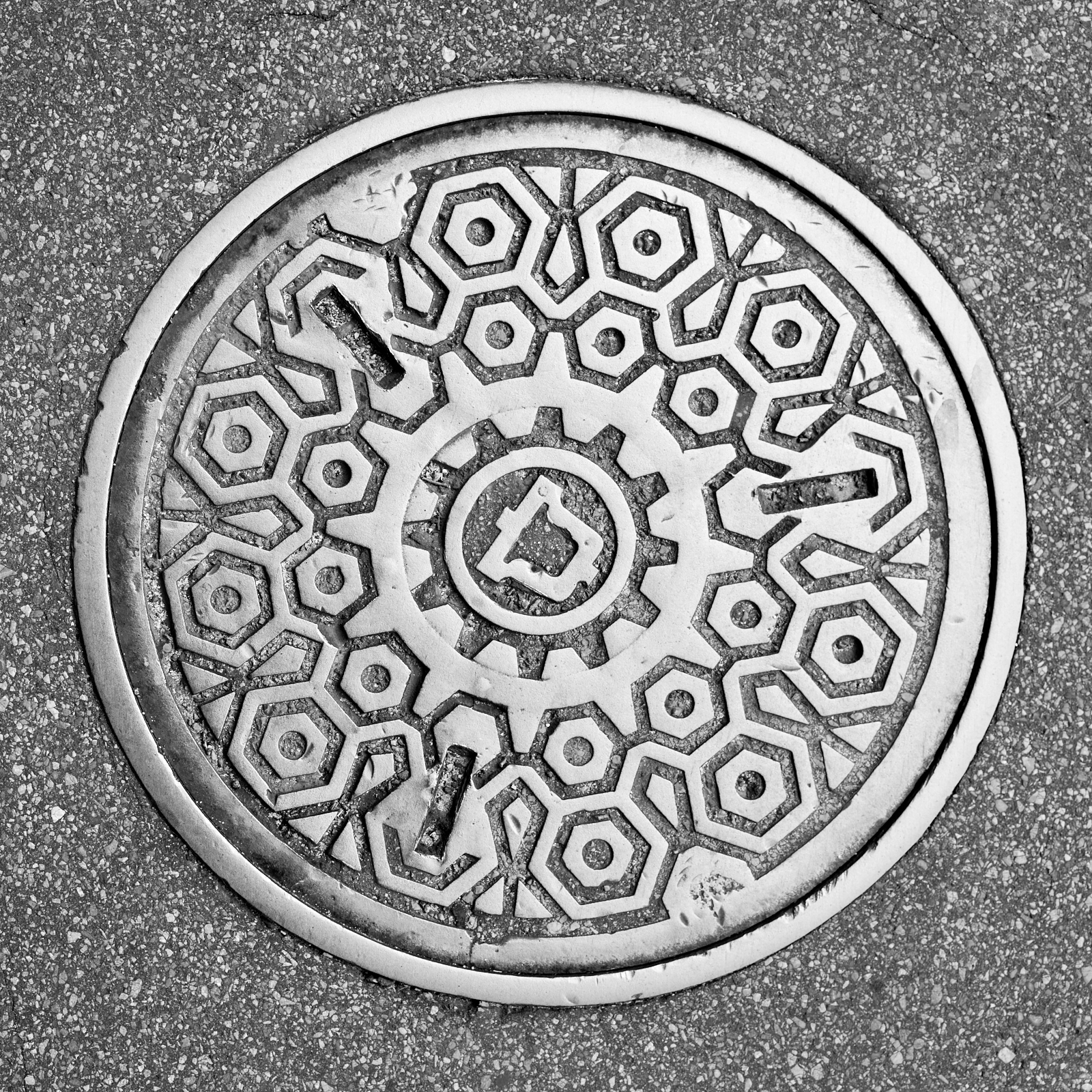 Infrastructure #220621.2. A black and white photograph of a Bell Systems manhole cover in a street.