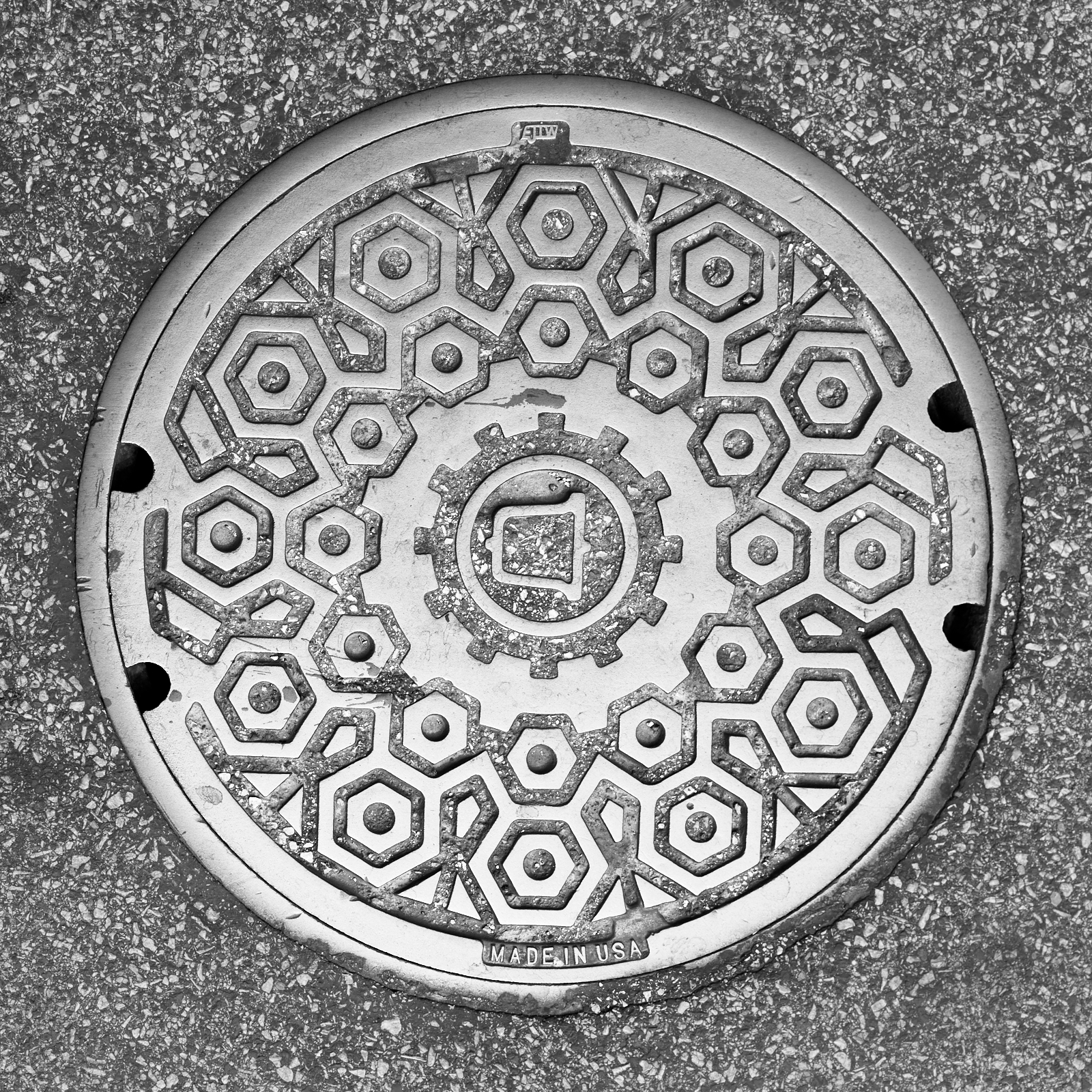 Infrastructure #220621.3. A black and white photograph of a Bell Systems manhole cover in a street.