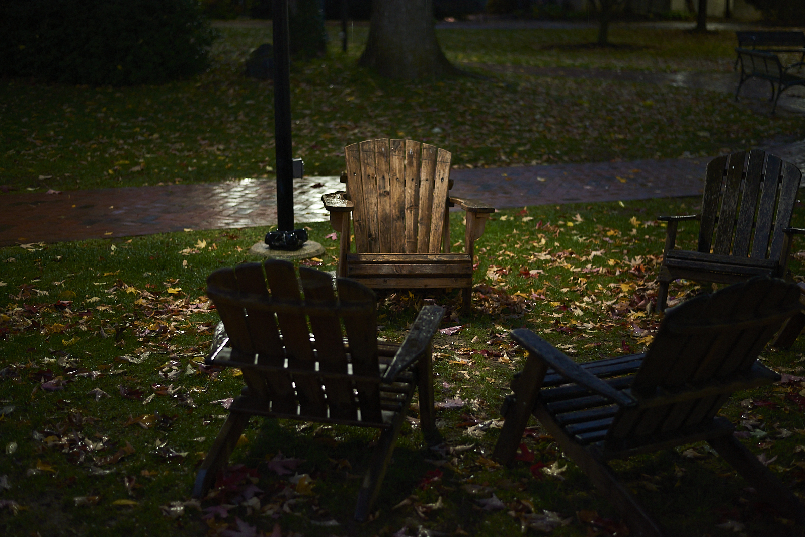 Urban #221017.2 Four Adirondack chairs in a pool of light on a rainy evening.