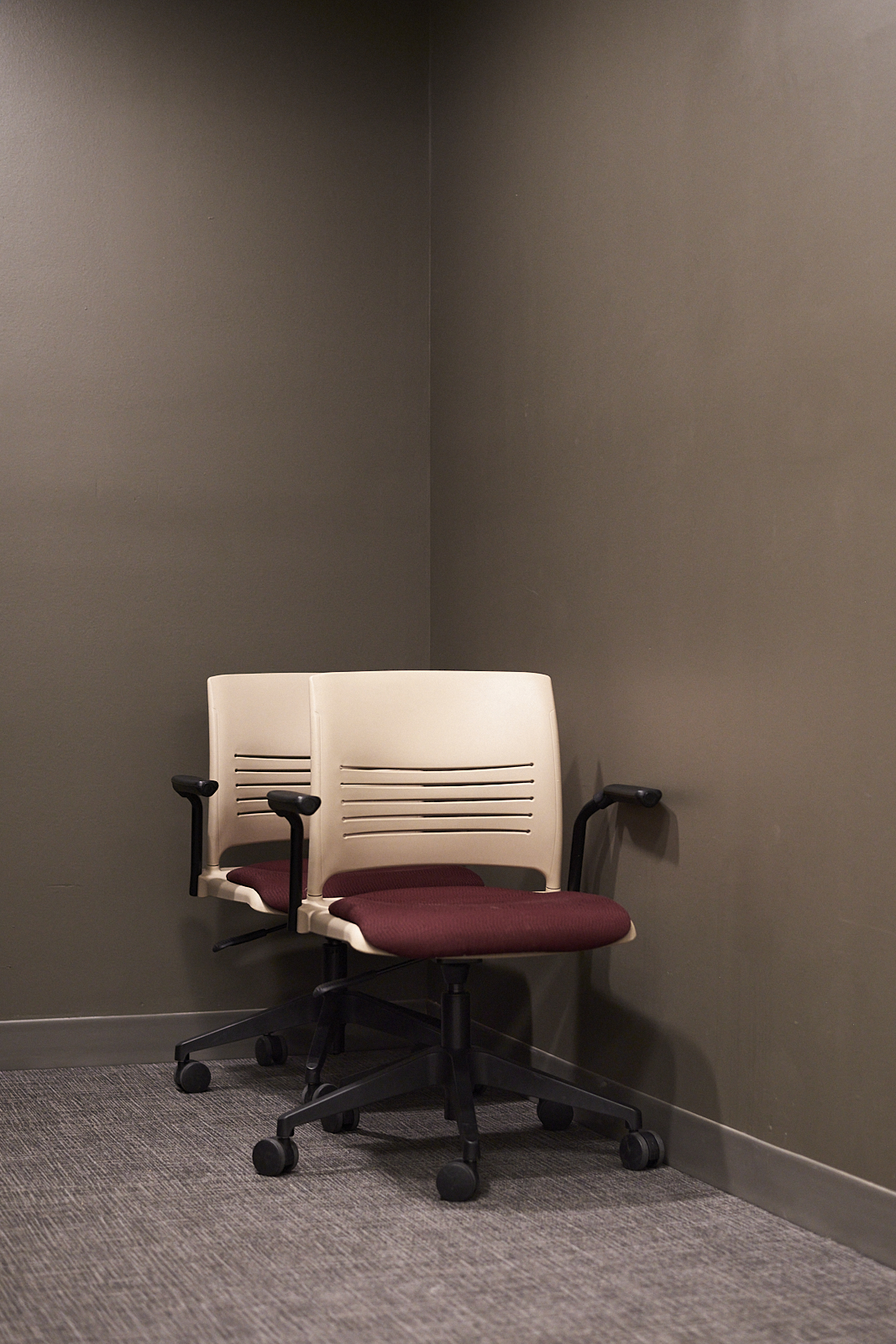 Interior #220226.0. A color photograph of two chairs on wheels in the corner of a room.