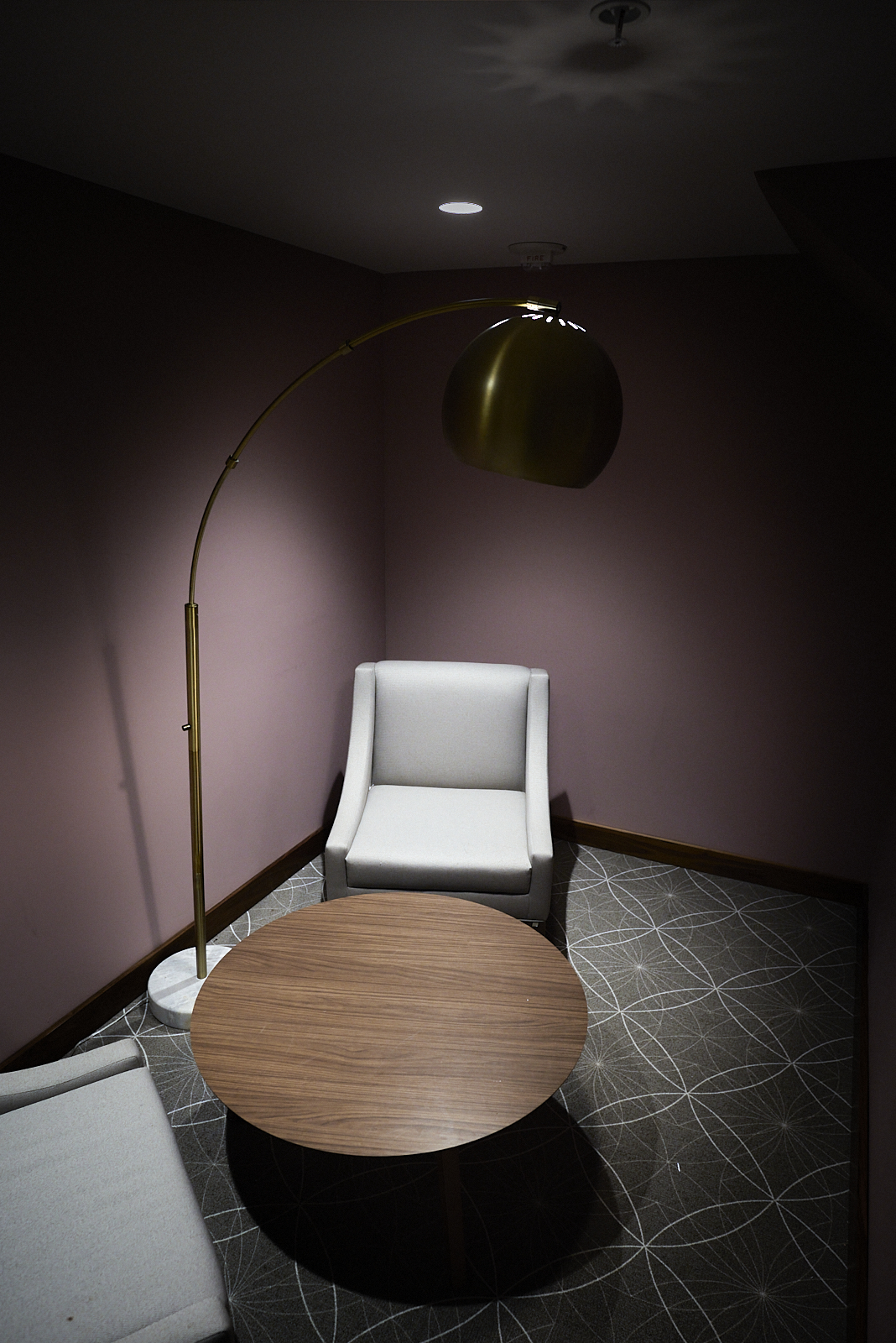 Interior #230106. A color photograph of an armchair and a table illuminated by a floor lamp and a recessed light.