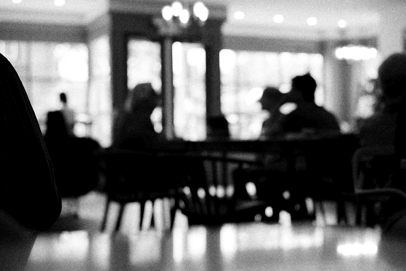 Black and white photograph of three people sitting at a table in a coffee shop.