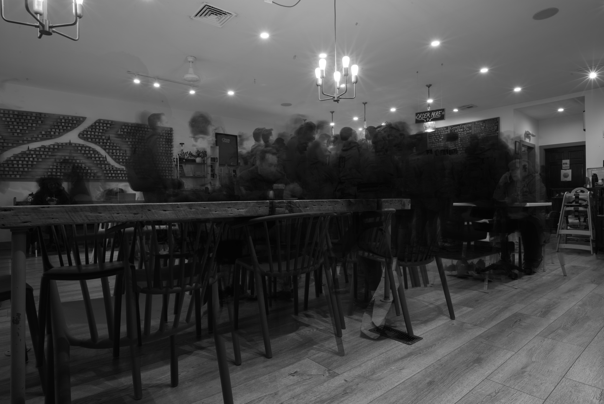 Black and white photo inside a cafe. All the patrons are blurred out.