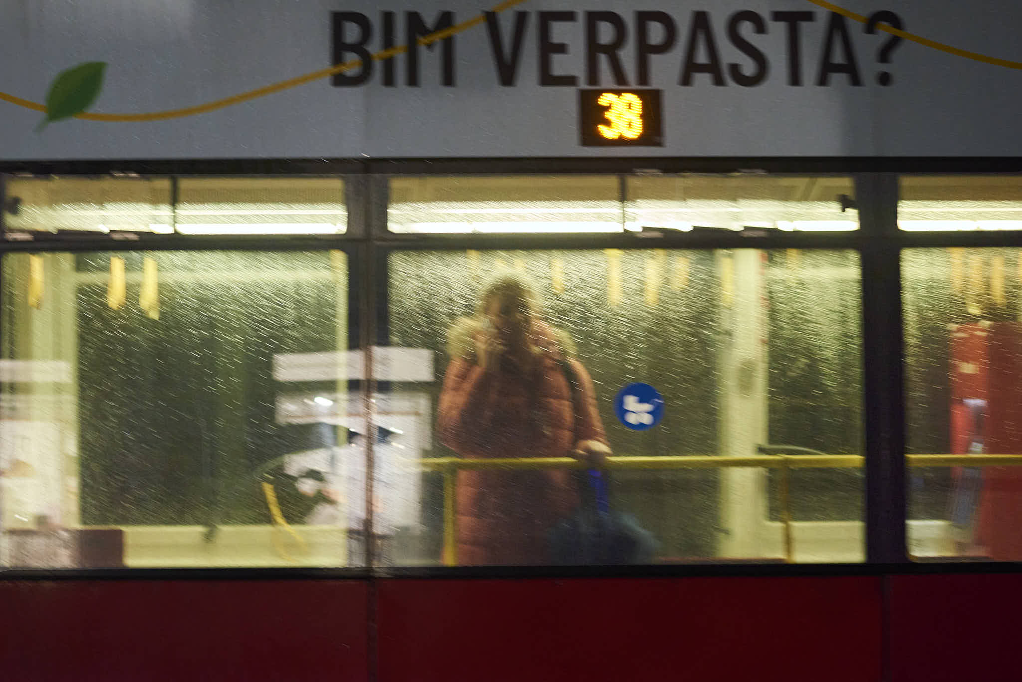 Color photo of a woman in a streetcar on a rainy night.