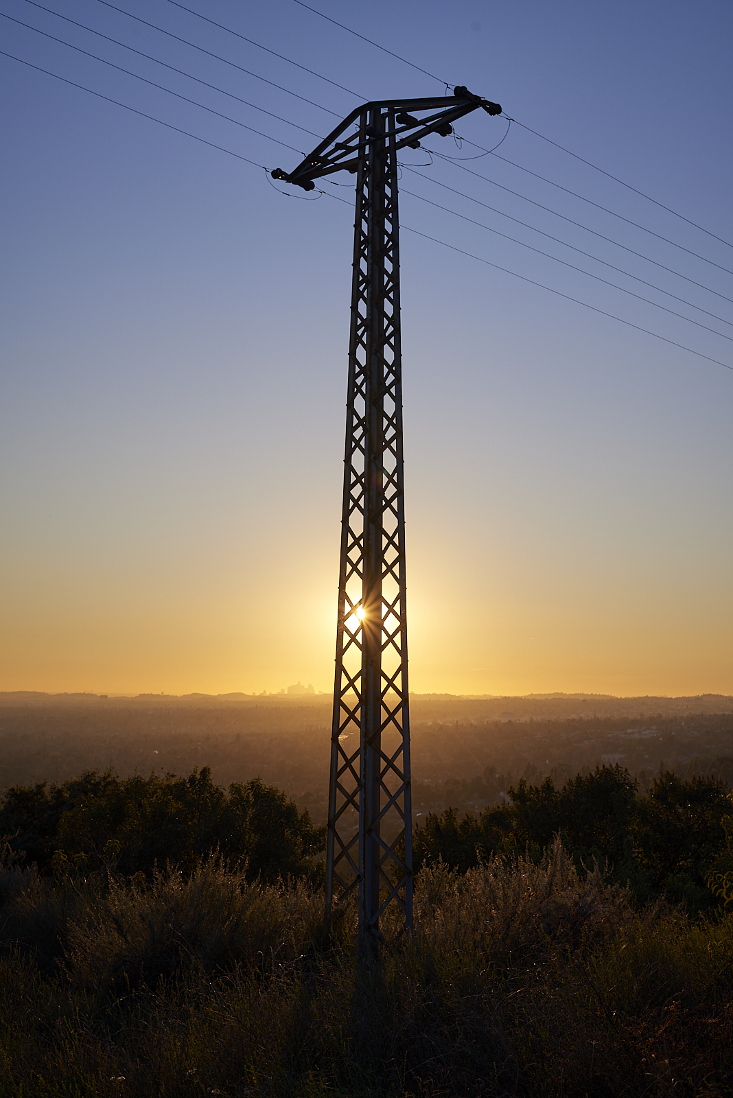 Urban #240105. A color photo of a utility pole with the sun setting behind it.